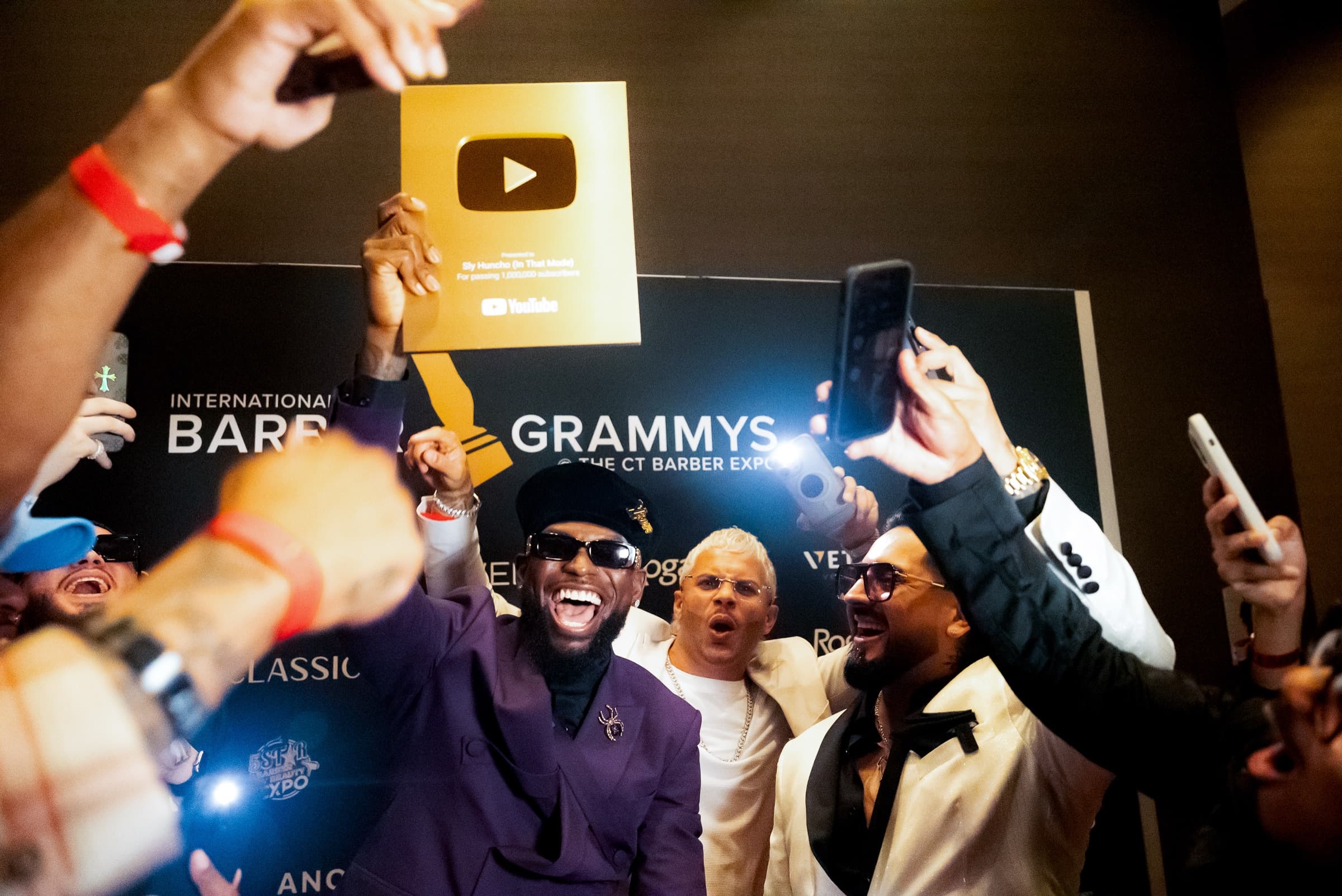 Sly Huncho celebrating with a creator award at a barber expo